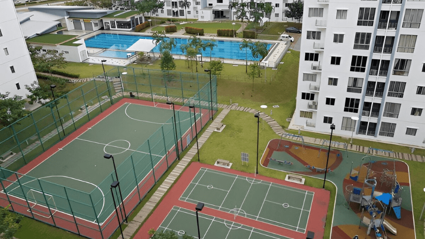 Aerial view showcasing various amenities, such as tennis court, children's area and a swimming pool adjacent to a high-rise apartment building.